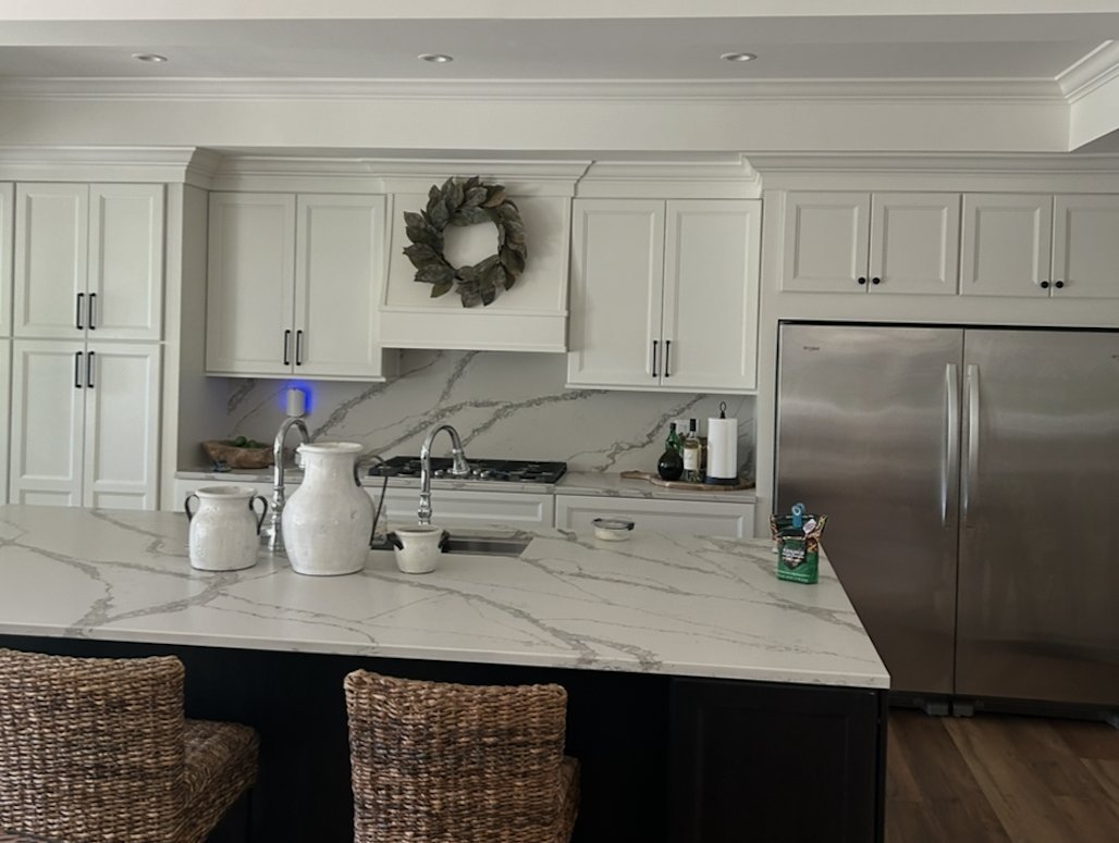 White kitchen with a marble-look quartz island, full-height backsplash and dark island cabinets by Burson Construction, Bluffton SC